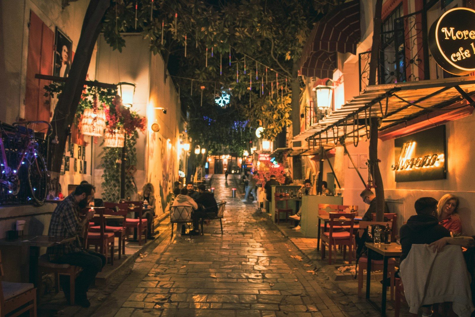 A narrow street with people sitting at tables